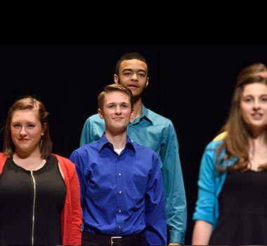 Ovation Awards, 5 Student with brightly colored shirts stand still on stage